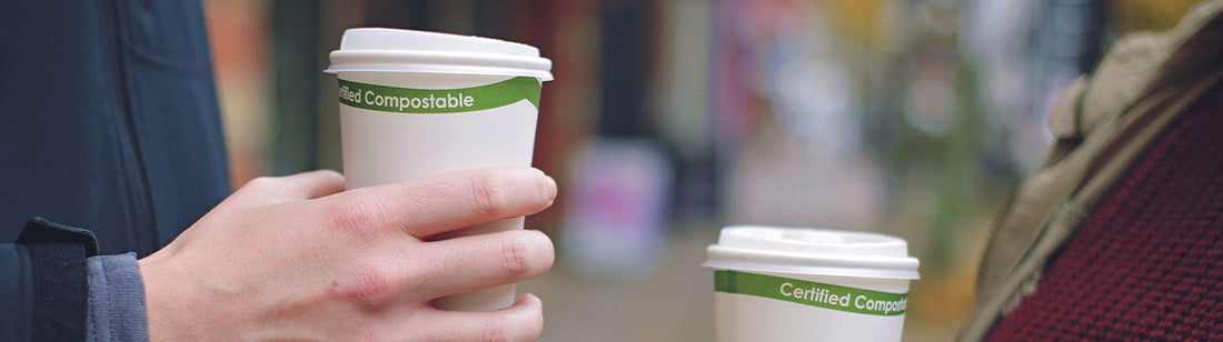 two humans holding white compostable hot cups