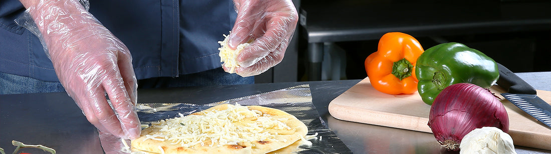 person putting toppings on a pizza while wearing poly gloves