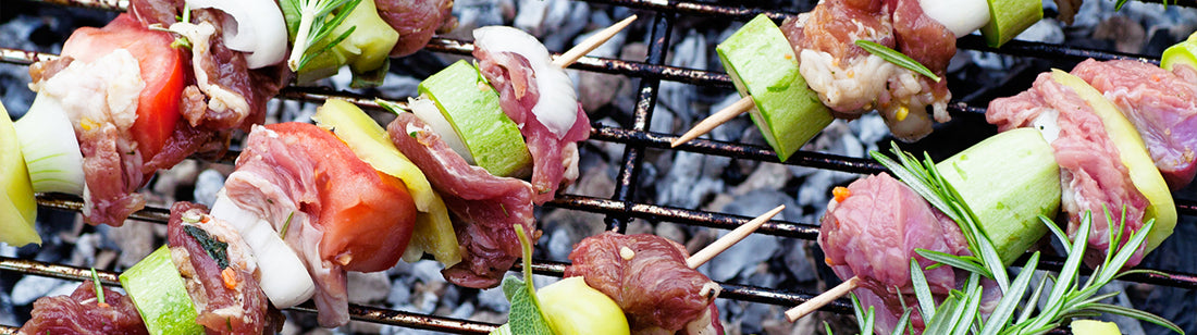 meat and veggies on skewers cooking on a bbq grill