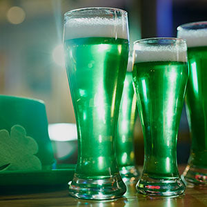 glasses of green beer next to a green hat