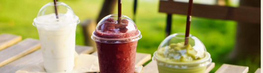 Three smoothies in plastic cups with plastic dome lids
