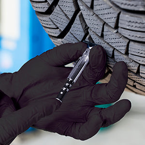 mechanic wearing black nitrile gloves and doing a thing to a tire