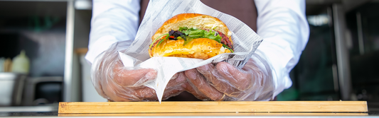 Person wearing poly gloves and holding a burger