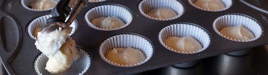 fresh batter being spooned in to fluted baking cups