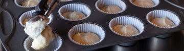 fresh batter being spooned into fluted baking cups