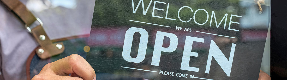 Shawn flipping a black welcome we are open sign in the window