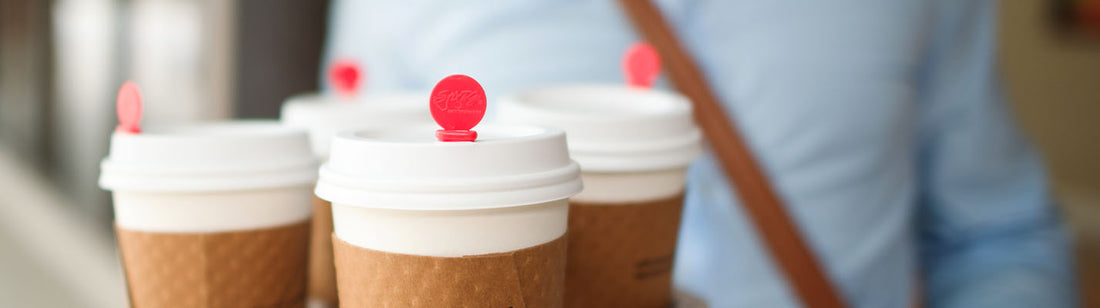 4 white coffee cups with red beverage plugs in the lids