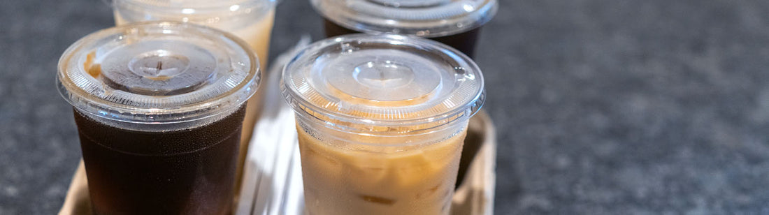 tray of 4 cold drinks in clear plastic cups with lids.