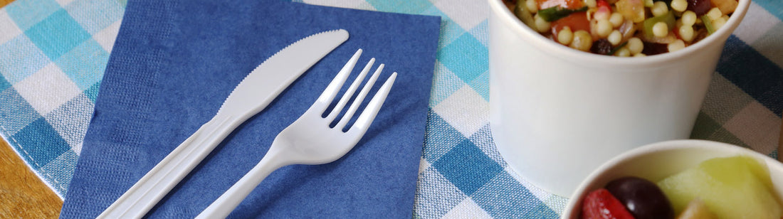 white plastic fork and knife on a blue napkin next two two white paper food cups