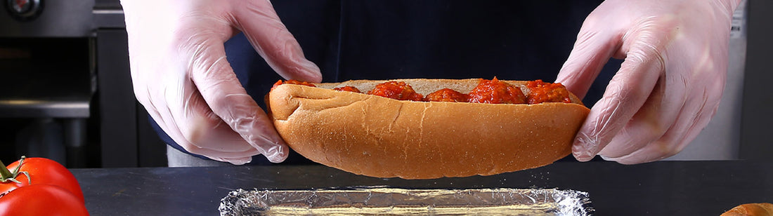 human wearing awear eco-friendly gloves and holding a meatball sub