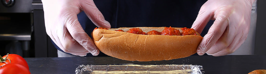 person wearing hybrid gloves and holding a meatball sub