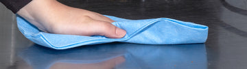 person wiping the counter with blue disposable towel