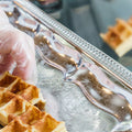 a gloved hand placing waffles on a silver tray