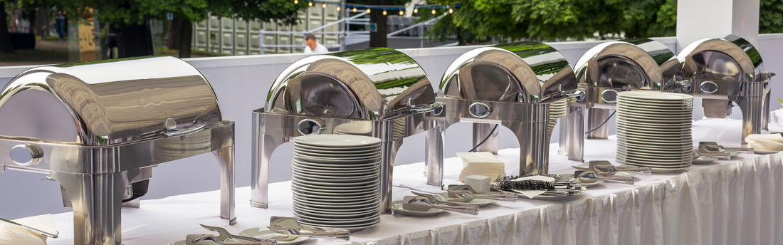 line of chafing dishes on a buffet table outdoors