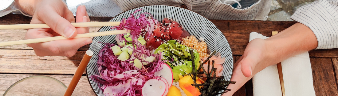 person eating a colourful rice bowl with chopsticks