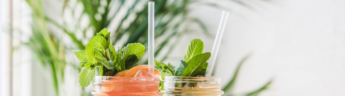 two jar mugs with fresh juice and clear compostable cellulosic straws inside