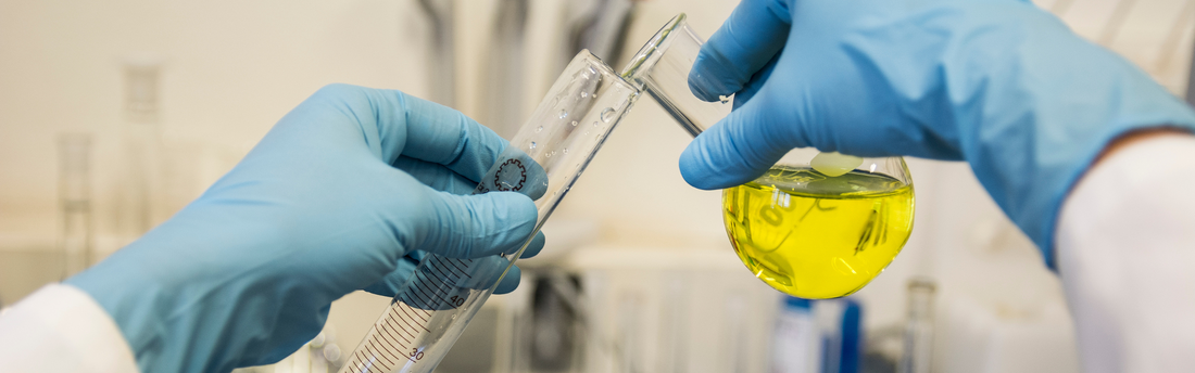 hands of a scientist in blue nitrile gloves pouring chemicals
