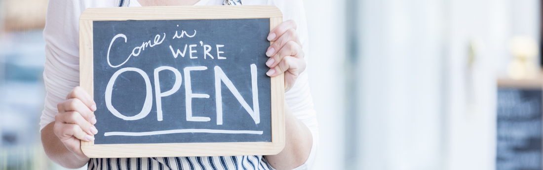 Person holding restaurant sign that says come in we're open