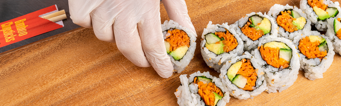 Person wearing hybrid gloves and plating fresh sushi on a primeware 10" x 5" rectangular molded fiber plate