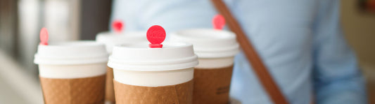 4 paper coffee cups in a tray with a red plug stick in the lid