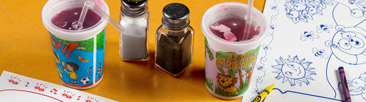 two colorful plastic kids cups next to coloring page placemats