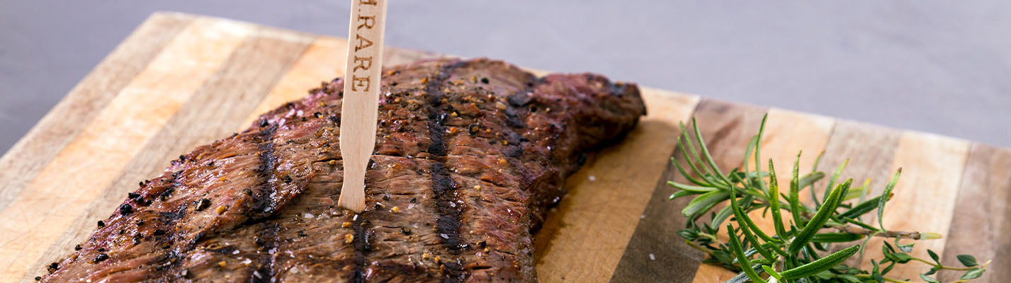 wooden steak marker in a cooked piece of steak on a wooden cutting board