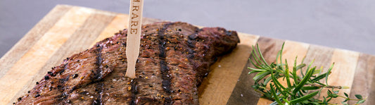 wooden steak marker in a cooked piece of steak on a wooden cutting board