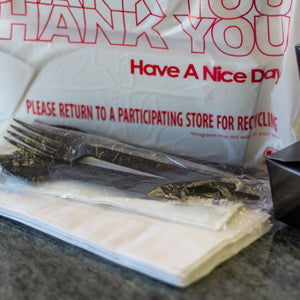 cutlery kit in package next to a bag of takeout