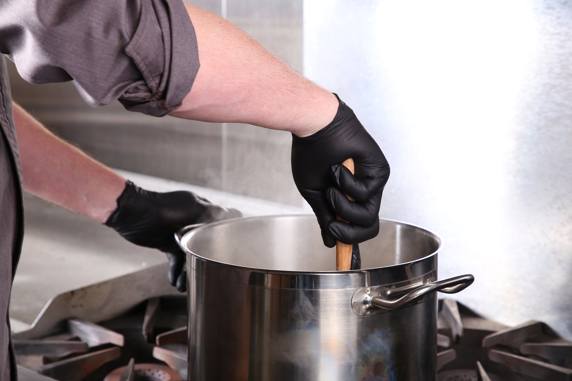 person wearing Powder-Free Black Nitrile Verge Gloves and stirring a large pot
