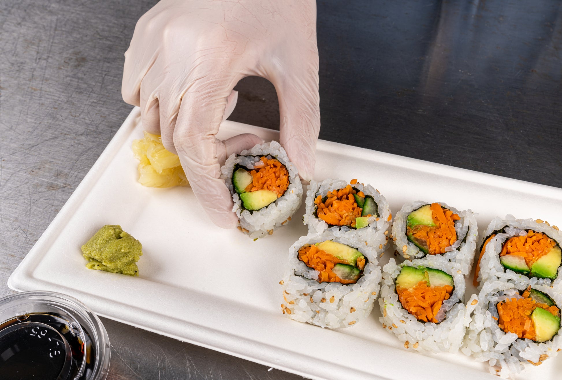 Person placing fresh sushi on a 10" x 5" Heavy Molded Rectangle Fiber Plates