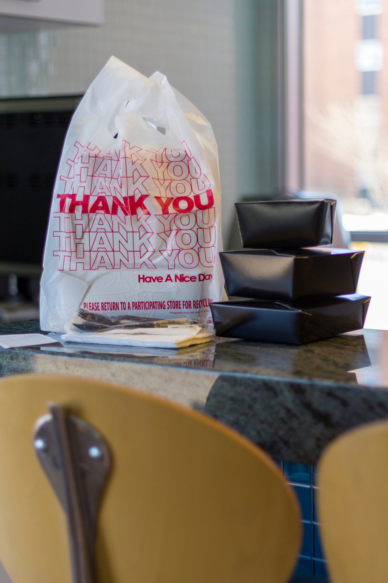 folded black takeout boxes next to a takeout bag