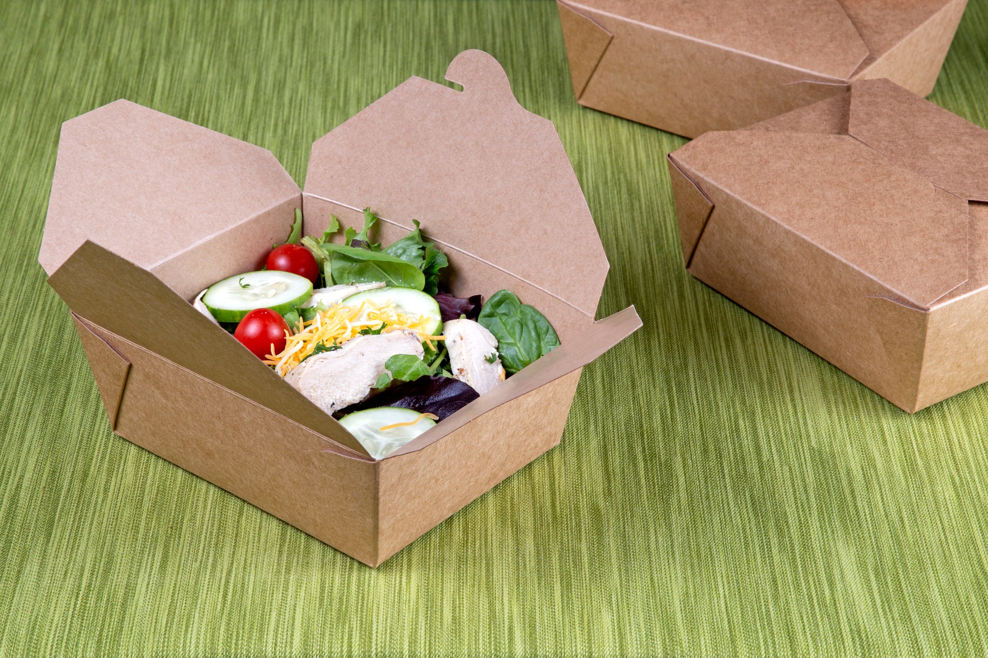 6" x 4-3/4" x 2.5" #8 Kraft Folded Takeout Box with Salad on a table with other packages in the background