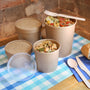 various sizes of kraft paper food container with food in them set out on a table