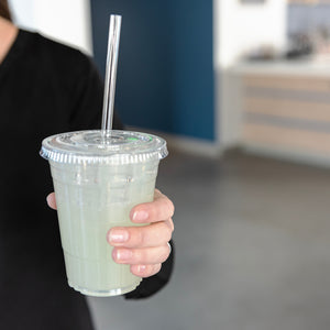 person holding up a lemonade in a clear cup with a clear compostable cellulosic straw